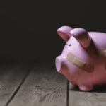 Broken piggy bank with band aid bandage or plaster finance background concept for economic recession or bankruptcy