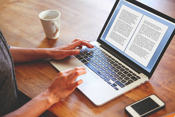 High angle image of a female novelist or blogger, typing on the laptop keyboard while having a cup of coffee. Retro processed with vibrant colors.