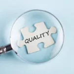 The word Quality on puzzle piece with magnifying glass